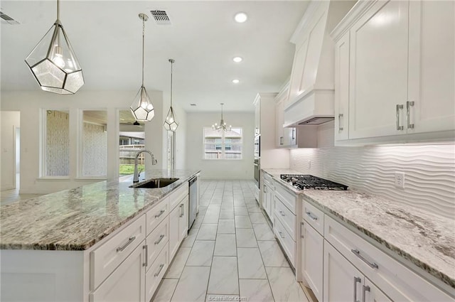 kitchen with premium range hood, pendant lighting, sink, white cabinets, and a large island