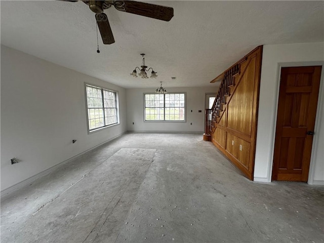 unfurnished living room featuring ceiling fan with notable chandelier