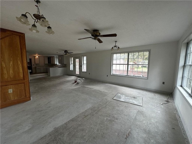 unfurnished living room featuring ceiling fan with notable chandelier