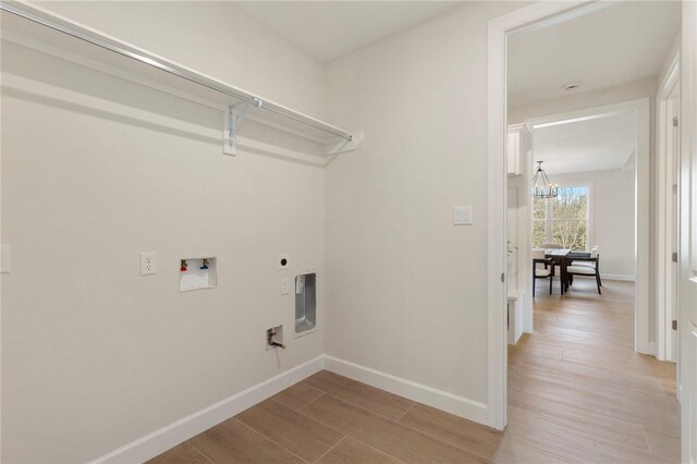 3223 Tamy Ln, Brenham, TX 77833 - laundry room featuring hookup for a washing machine, light wood-type flooring, baseboards, and a chandelier
