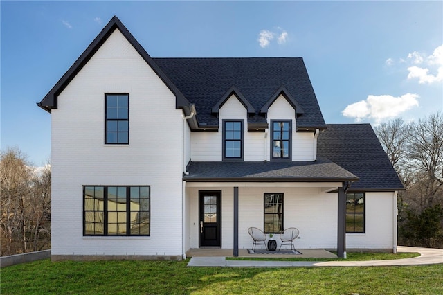 3223 Tamy Ln, Brenham, TX 77833 - modern inspired farmhouse featuring covered porch, a shingled roof, a front yard, and brick siding