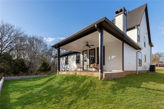 3223 Tamy Ln, Brenham, TX 77833 - rear view of house featuring central air condition unit, ceiling fan, a lawn, a chimney, and a patio