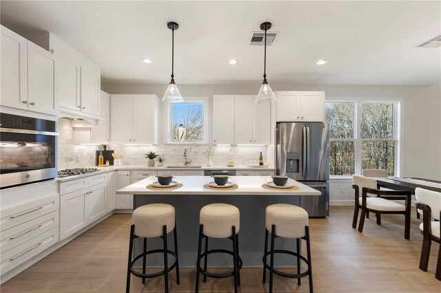 3223 Tamy Ln, Brenham, TX 77833 - kitchen featuring appliances with stainless steel finishes, a sink, a kitchen island, a breakfast bar area, and decorative backsplash