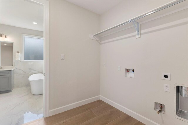 3223 Tamy Ln, Brenham, TX 77833 - laundry area featuring electric dryer hookup, washer hookup, baseboards, and wood finished floors