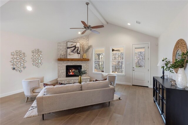 3223 Tamy Ln, Brenham, TX 77833 - living room featuring beam ceiling, light wood finished floors, a stone fireplace, healthy amount of natural light, and a ceiling fan