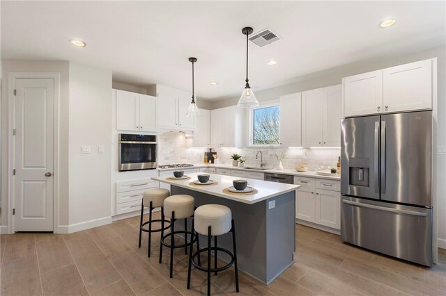 3223 Tamy Ln, Brenham, TX 77833 - kitchen with appliances with stainless steel finishes, a sink, a kitchen breakfast bar, light wood-type flooring, and white cabinetry