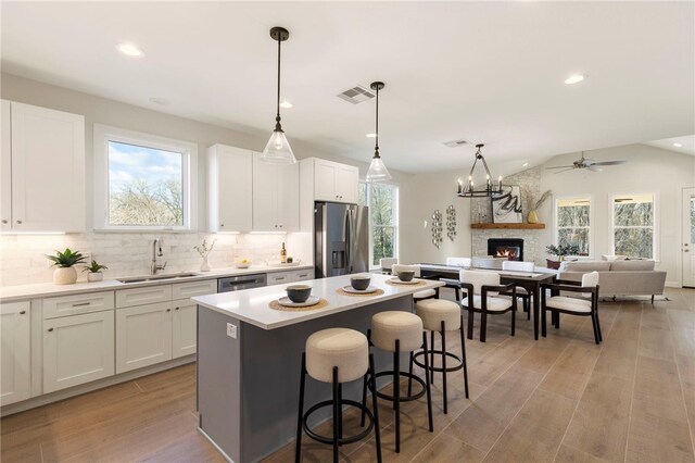 3223 Tamy Ln, Brenham, TX 77833 - kitchen with appliances with stainless steel finishes, a sink, a fireplace, a center island, and decorative backsplash