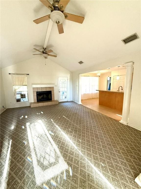 unfurnished living room featuring a tile fireplace, carpet floors, ceiling fan, and lofted ceiling