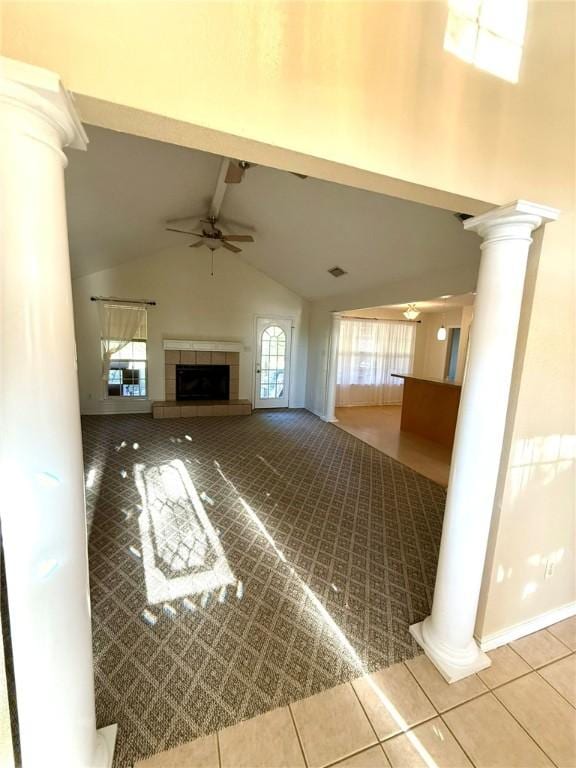 unfurnished living room featuring tile patterned floors, ceiling fan, high vaulted ceiling, beamed ceiling, and a tiled fireplace