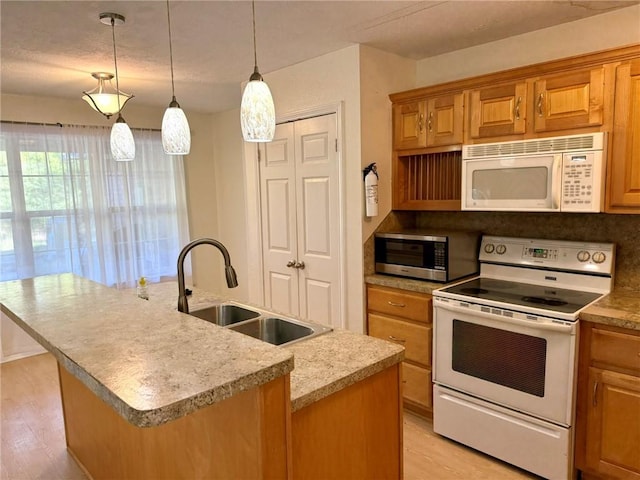 kitchen featuring a center island with sink, sink, range with electric cooktop, hanging light fixtures, and light hardwood / wood-style floors