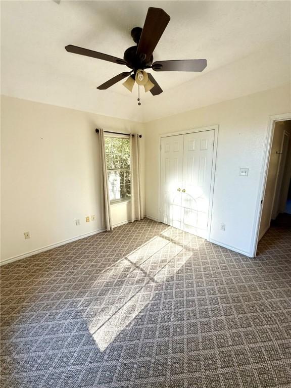 unfurnished bedroom with carpet flooring, ceiling fan, and a closet