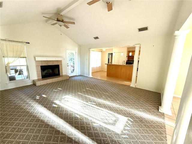 unfurnished living room featuring a tile fireplace, high vaulted ceiling, ceiling fan, beamed ceiling, and carpet floors