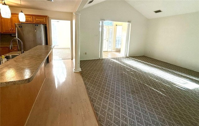 interior space with pendant lighting, lofted ceiling, sink, stainless steel fridge, and light hardwood / wood-style floors