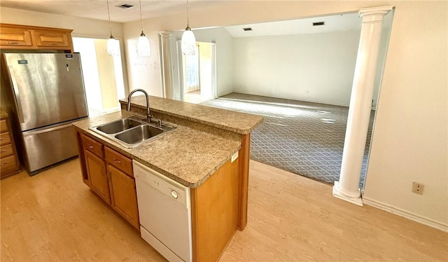 kitchen featuring decorative columns, sink, a center island with sink, dishwasher, and stainless steel refrigerator