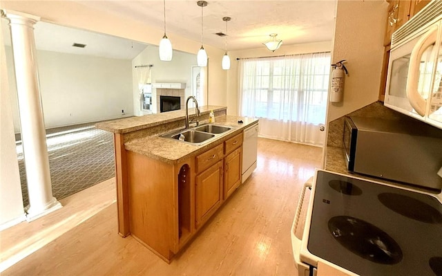 kitchen featuring ornate columns, sink, light hardwood / wood-style flooring, white appliances, and a kitchen island with sink