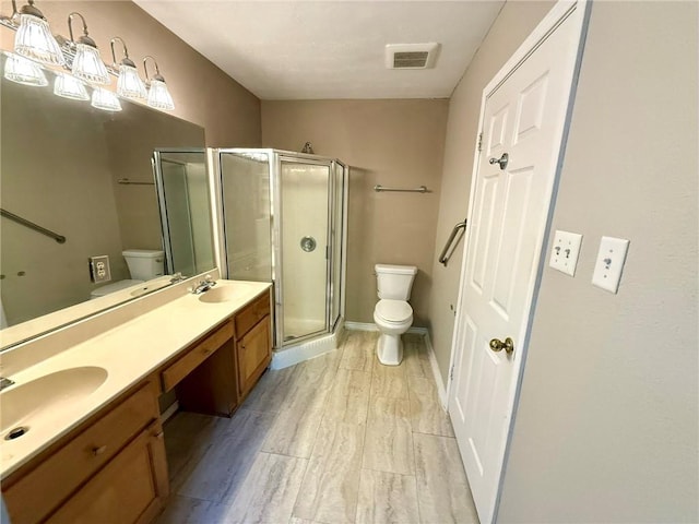 bathroom with a shower with door, vanity, and toilet