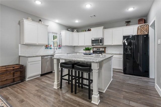 8729 Nathan Dr, Waller, TX 77484 - kitchen featuring stainless steel appliances, a center island, white cabinets, tasteful backsplash, and recessed lighting