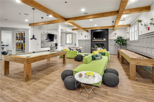 game room featuring a fireplace, light wood-type flooring, pool table, beam ceiling, and french doors