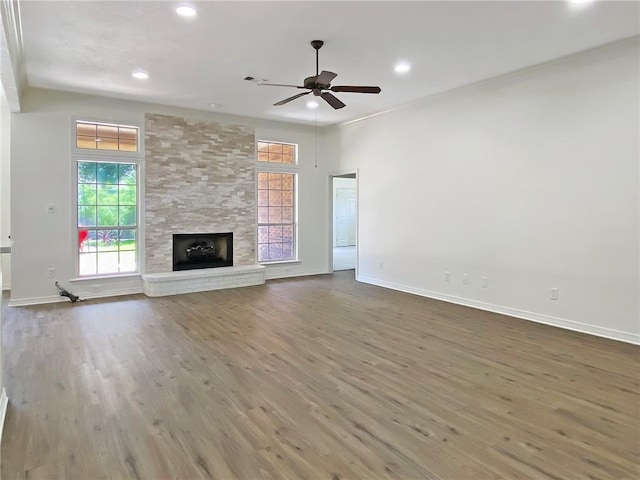 unfurnished living room with wood-type flooring, a large fireplace, and ceiling fan