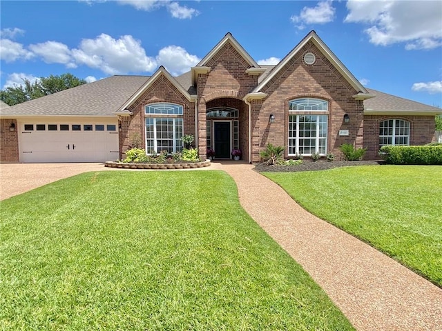 view of front of home featuring brick siding, roof with shingles, a garage, driveway, and a front lawn