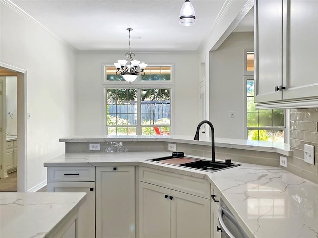 kitchen featuring crown molding, decorative light fixtures, light stone countertops, and sink