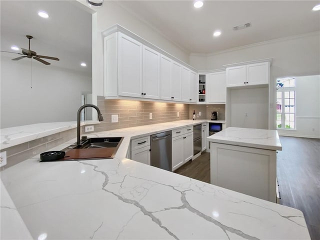 kitchen featuring sink, white cabinets, backsplash, stainless steel dishwasher, and light stone countertops