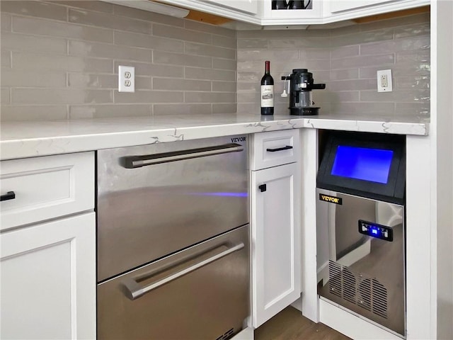 kitchen featuring backsplash, light stone countertops, and white cabinets