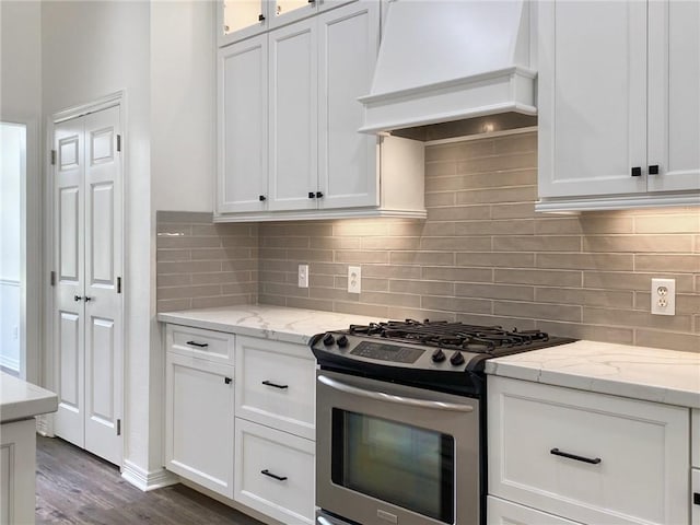 kitchen with premium range hood, white cabinets, decorative backsplash, gas stove, and light stone countertops