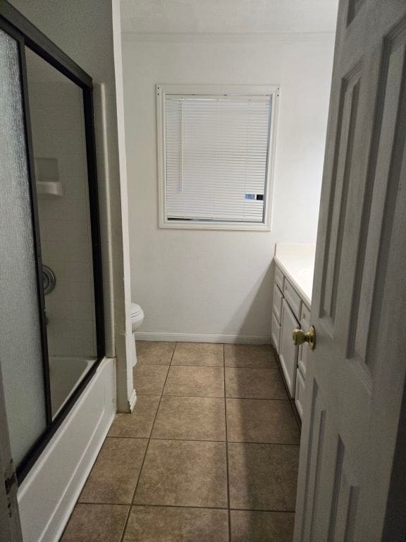 full bathroom featuring toilet, vanity, tile patterned floors, and bath / shower combo with glass door