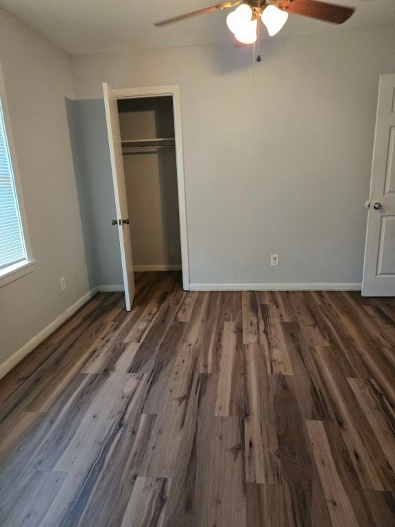 unfurnished bedroom with ceiling fan, a closet, and dark hardwood / wood-style floors