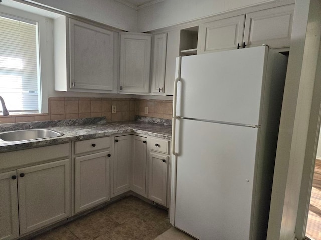 kitchen with sink, white refrigerator, backsplash, white cabinets, and dark tile patterned flooring