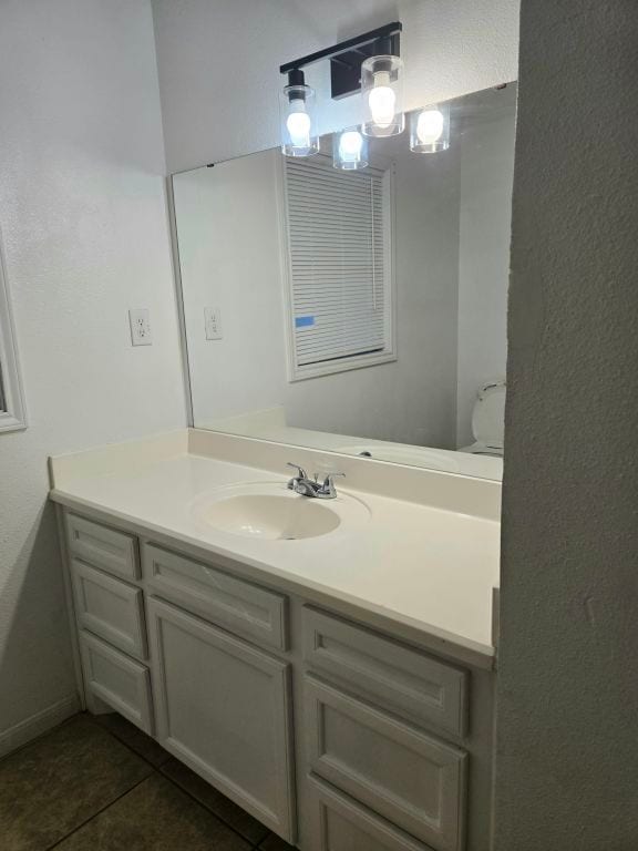 bathroom with toilet, vanity, and tile patterned floors