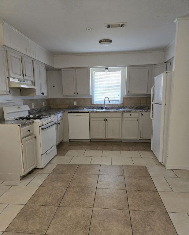 900 E 27th St, Bryan, TX 77803 - kitchen with white appliances, under cabinet range hood, a sink, decorative backsplash, and crown molding