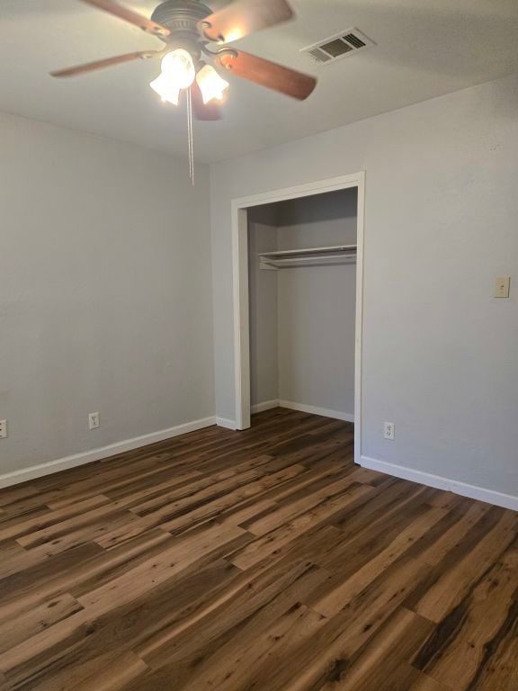 unfurnished bedroom with a closet, ceiling fan, and dark hardwood / wood-style flooring