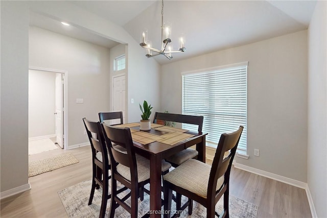 dining room with a notable chandelier, light hardwood / wood-style floors, and vaulted ceiling