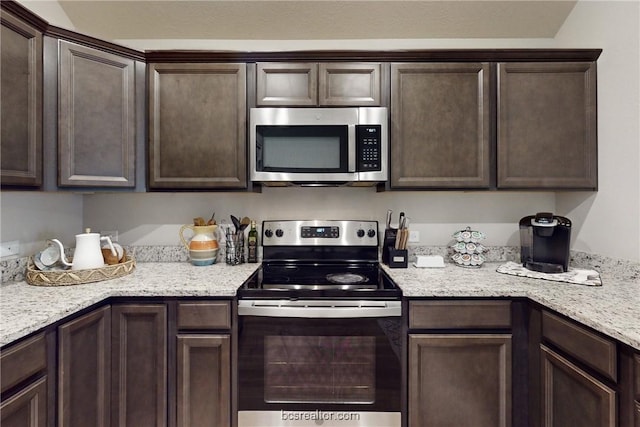 kitchen featuring dark brown cabinetry, light stone counters, and stainless steel appliances