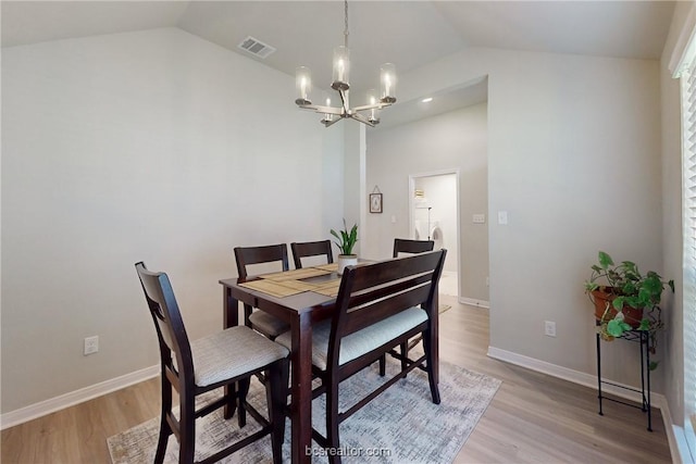 dining room featuring a chandelier, light hardwood / wood-style floors, and vaulted ceiling