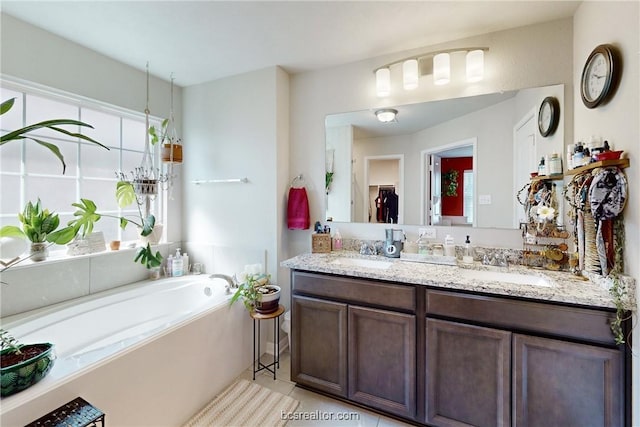 bathroom with a washtub, vanity, and tile patterned flooring