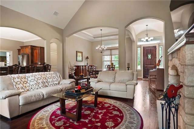 living room featuring a notable chandelier, dark hardwood / wood-style floors, lofted ceiling, and ornamental molding