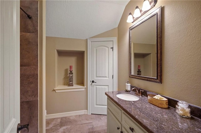 bathroom with a textured ceiling, vanity, and lofted ceiling