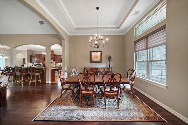 dining room featuring dark hardwood / wood-style flooring, a raised ceiling, crown molding, and an inviting chandelier