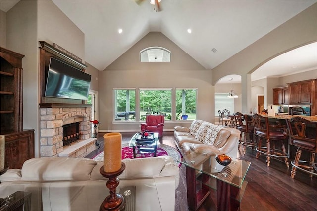 living room featuring a fireplace, dark hardwood / wood-style floors, high vaulted ceiling, and a chandelier