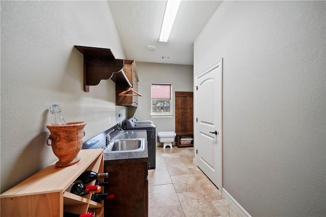 laundry room with cabinets, washer / dryer, sink, and a textured ceiling