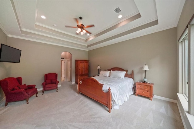 bedroom featuring ceiling fan, a raised ceiling, light colored carpet, and ornamental molding