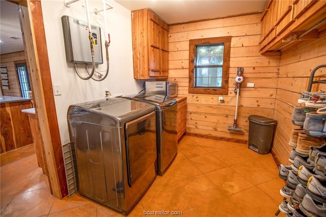 laundry room featuring wood walls, washer and clothes dryer, light tile patterned flooring, and cabinets