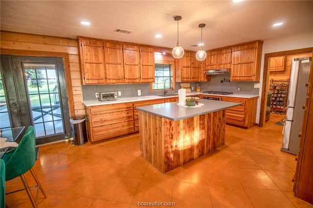 kitchen with decorative light fixtures, a kitchen island, light tile patterned flooring, and tasteful backsplash