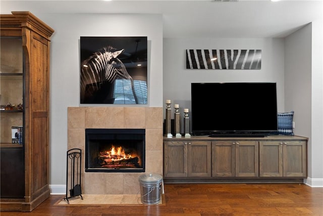 living room featuring dark wood-type flooring and a tile fireplace