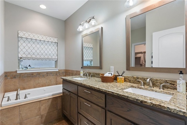 bathroom with vanity and tiled bath