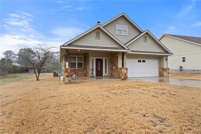 view of front of home with cooling unit, a garage, a front yard, and covered porch