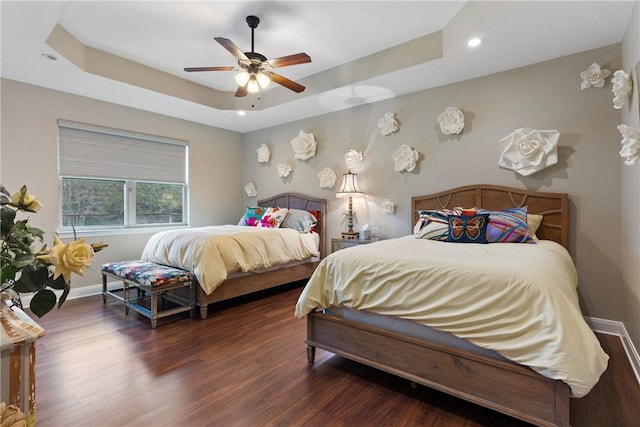 bedroom featuring a tray ceiling, dark wood-type flooring, and ceiling fan